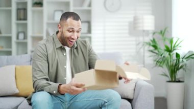 Karton kutuları açan heyecanlı genç adam içine bak, hızlı teslimat servisi tarafından şaşırtılan erkek, sipariş edilmiş alımdan memnun olan mutlu müşteri, online alışveriş elemanı, açık paket tüketicisi posta paketi alıyor.