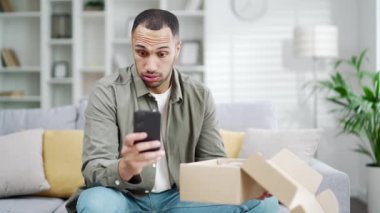 Kızgın, hoşnutsuz bir müşteri Arap 'a kırık karton kötü paket teslimatı kutusu veriliyor. Negatif alışveriş deneyimine sahip cep telefonuyla şikayetler yazılıyor. Ev içinde olumsuz geri bildirim veriliyor.