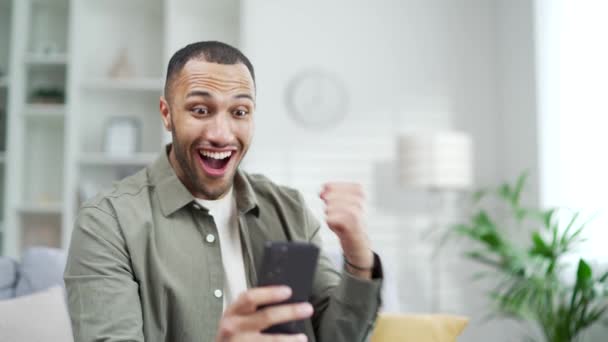 惊喜交集的幸运儿在家里看了手机短信后高兴极了兴奋的男人看着屏幕 高兴地收到了好消息在智能手机室内大获全胜胜利胜利胜利在线赌博 — 图库视频影像