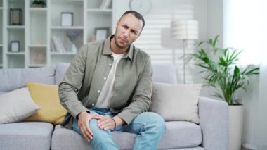 Eklem ve Diz Ağrısı Kişisi karışık ırkçı bacak travması ya da eklem iltihabı yaşıyor. Yaralanan kas krampını azaltmak için kaslara masaj yapmak. Oturma odasında kanepede oturmak.