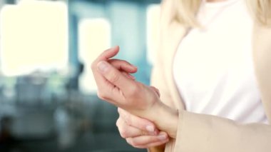 Modern bir ofisteki bir iş yerinde otururken bileğine masaj yapan bir kadının elini kapat. Takım elbiseli bir kadın çalışan eklem ağrısı çeker, yaralanır, ağrıyan bir kası ovalar, egzersiz yapar.