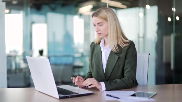 一位穿着西装的年轻自信的女商人坐在现代化的办公室里工作时 在笔记本电脑上打字 从事计算机项目 发短信或网上聊天的女雇员 — 图库视频影像