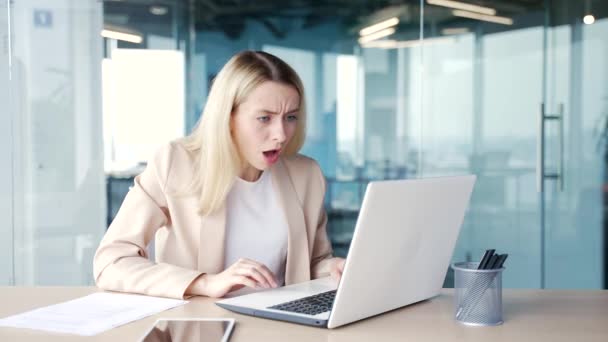Chockad Ung Affärskvinna Läser Dåliga Nyheter Laptop När Sitter Arbetsplatsen — Stockvideo