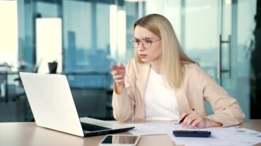 Genç kadın muhasebecinin ofiste otururken dizüstü bilgisayarla işi konusunda kafası karışmış. Üzgün bir iş kadını bilgisayar ekranına bakar, ellerini açar ve sorunu anlayamaz.
