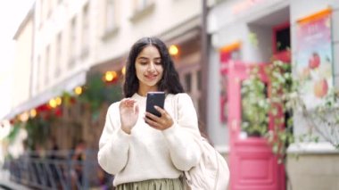 Çekici, genç, Hintli, Hintli, genç bir turist. Şehir caddesinde yürüyen, akıllı cep telefonu kullanan, internette gezen, teknolojiyi ve hayat tarzı seyahatini arayan bir turist.