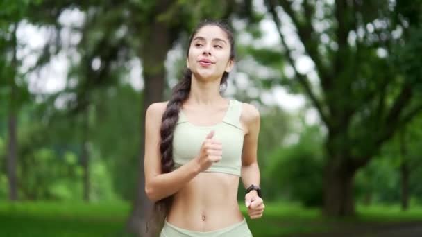 若い成人女性ランナーが都市公園でジョギング ハッピーブルネットスポーツウーマンは 屋外でジョギングを楽しんでいます 美しいフィット感のインドのアラビアの女性が朝の走行をしています 健康的なライフスタイルをコンセプト — ストック動画