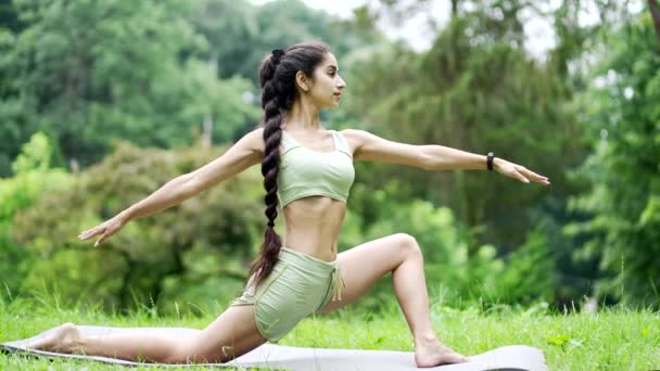 年轻女子在公园或森林的树上 坐在垫子上练习普拉提或瑜伽 户外做体操 体格健壮的印度女子健美运动员进行肌肉伸展运动 — 图库视频影像