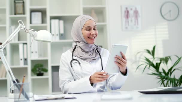 Médica Muçulmana Casaco Branco Falando Videochamada Usando Tablet Clínica Hospitalar — Vídeo de Stock