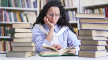 Kampüs kütüphanesinde kitap okuyarak ders çalışan yorgun bir kız öğrenci. Üniversitede sınav döneminde esmer bir kızın öğrenme yorgunluğu. Çok çalışan aday giriş sınavları için hazırlanıyor