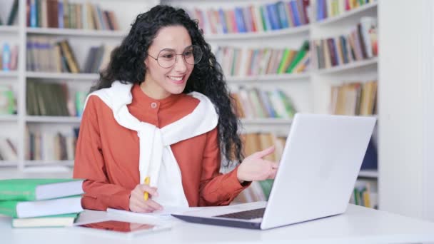 网上电子学习的女学生在校园图书馆使用手提电脑记录笔记或录像 给远程教师打电话 布鲁内特妇女申请者正在准备在课堂上参加大学考试 — 图库视频影像