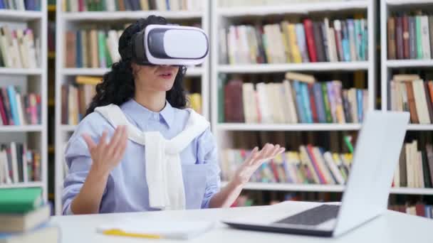 成功的女生在校园图书馆的虚拟现实模拟器中使用虚拟现实眼镜进行视频通话和在线聊天 一个自信的导师有一个远程会议 虚拟会议 — 图库视频影像