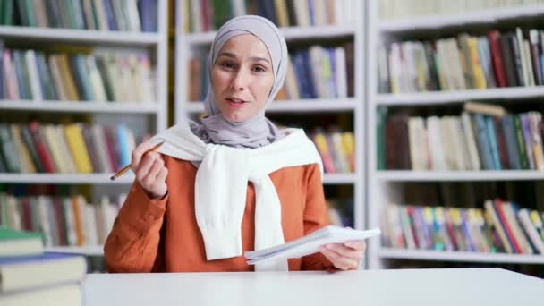 ウェブカメラビュー ヒジャーブのイスラム教徒の女性学生は キャンパス図書館スペースでビデオ通話でオンラインEラーニングをリストアップします 教師は 学生のためのトレーニングを持っています コースを実施 リモートで話す — ストック動画