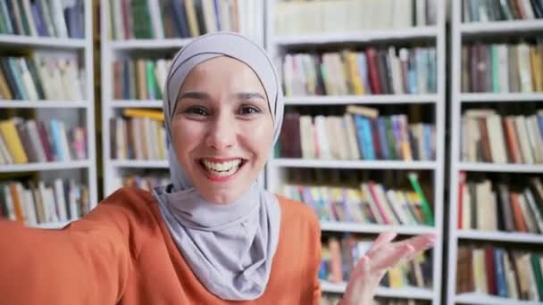Pov Webcam View 穿着头巾的穆斯林女学生在校园图书馆里用智能手机用视频通话 积极乐观的女孩在课堂上自言自语时 与朋友谈笑风生 — 图库视频影像