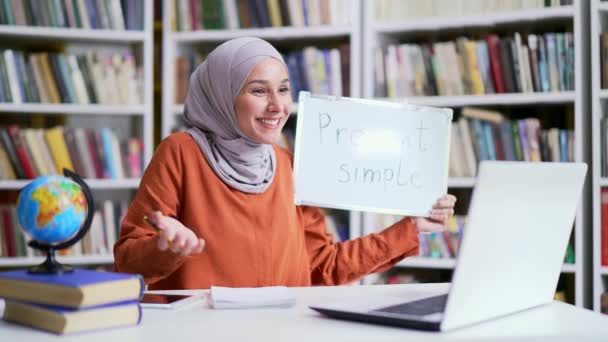 캠퍼스 도서관 공간에 앉아있는 노트북을 사용하여 비디오 수업을주는 히잡에서 긍정적 — 비디오