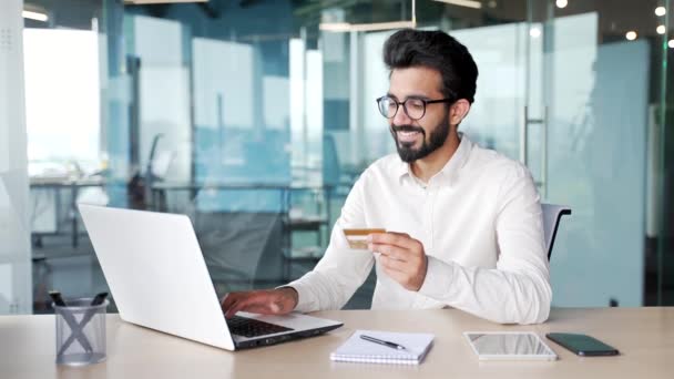 Uśmiechnięty Młody Brodaty Mężczyzna Wpisuje Numer Karty Kredytowej Laptopie Siedząc — Wideo stockowe