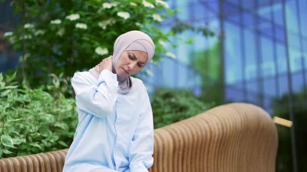 사무실 거리에 벤치에 앉아있는 히잡에서 무슬림 마사지와 그녀의 손으로 근육을 — 비디오