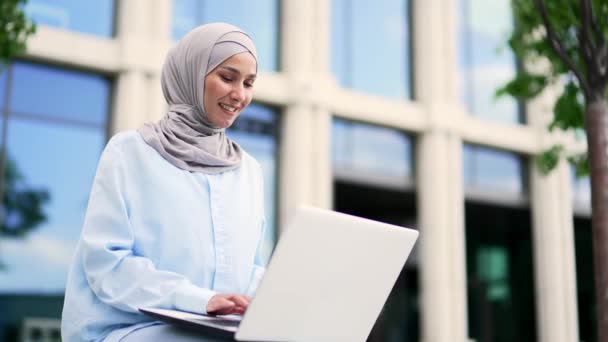 Молодая Мусульманка Работница Хиджабе Работает Ноутбуке Сидя Скамейке Возле Офисного — стоковое видео