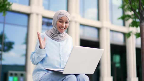 Młoda Muzułmanka Hidżabie Rozmawiająca Przez Telefon Wideo Pomocą Laptopa Siedząc — Wideo stockowe