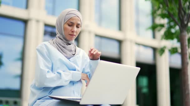 Przemyślana Skoncentrowana Młoda Muzułmanka Freelancerka Hidżabie Pracująca Laptopie Siedząc Ławce — Wideo stockowe
