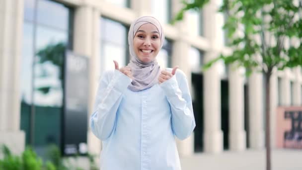 Νεαρή Χαμογελαστή Μουσουλμάνα Υπάλληλος Χιτζάμπ Δείχνει Τον Αντίχειρά Της Κοιτάζοντας — Αρχείο Βίντεο