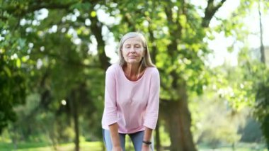 Yaşlı, aktif, gri saçlı kadın sabah parkında koşarken nefes darlığı çekiyor. Olgun, yaşlı bir kadın dizlerinin üzerine çöker alnındaki teri eliyle siler ve derin derin nefes alır.