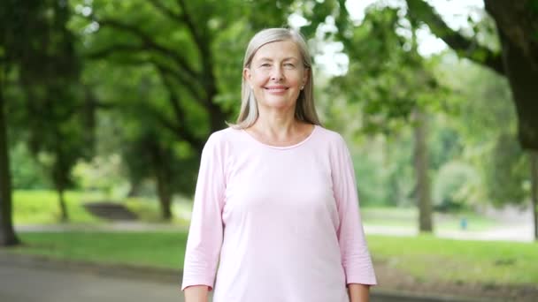 站在城市公园里的活跃的灰发老年妇女的画像 斯波蒂带着积极的女性退休了 她看着相机笑着 快乐的长跑者 在大自然中交叉着双臂 — 图库视频影像