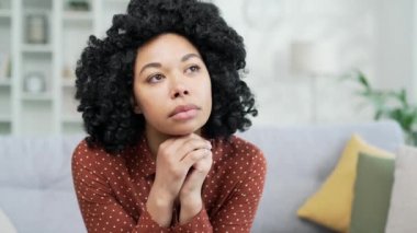 Evdeki oturma odasındaki kanepede oturan düşünceli, Afro-Amerikan bir kadının portresi. Yalnız siyah bir kadın melankolik bir ruh hali içindedir. Sıkılmış, ilgisiz hisseder, başka tarafa bakar, düşünür.