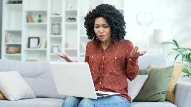 집에서 거실에서 소파에 노트북을 통화를 논쟁을 말하는 아프리카계 좌절한 여성은 — 비디오