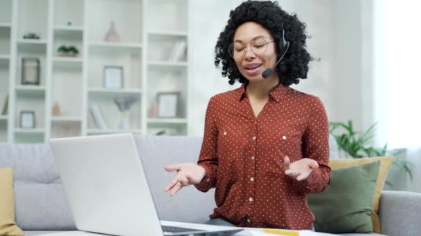一位自信的非洲裔美国女商人坐在家里的办公室里 坐在无线耳机里用笔记本电脑对着视频通话 黑人女教练进行远程在线培训 研讨会 网络研讨会 — 图库视频影像