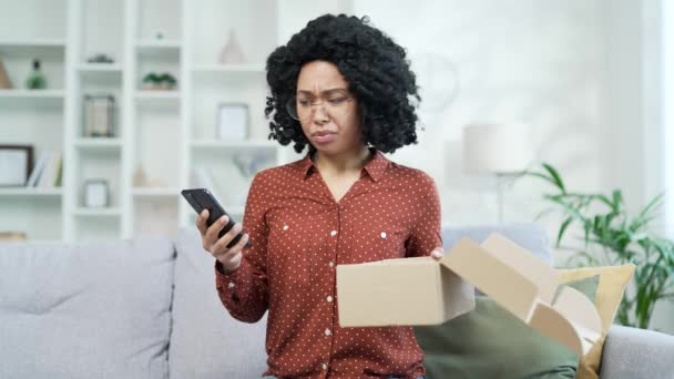 美国黑人女性在家里收到一个装有错误产品的包裹后 在智能手机上写了一篇糟糕的评论 黑人妇女不喜欢在网上商店购物 服务问题或受损物品 — 图库视频影像