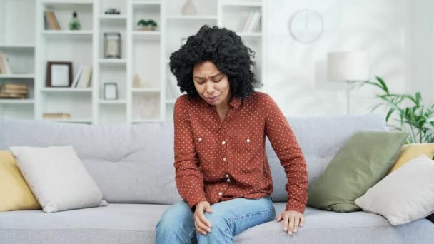 Młoda Afroamerykanka Cierpi Bolesny Ból Stawów Kolanowych Siedząc Kanapie Salonie — Wideo stockowe