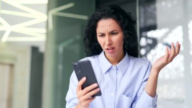 Kapatın. Genç bayan çalışanın modern ofisteki işyerinde otururken akıllı telefondan kötü haberler okumasına üzüldüm. Esmer kadın internetten gelen bir mesaj yüzünden hayal kırıklığına uğradı.