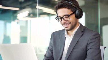 Kapatın. Resmi takım elbiseli, kablosuz kulaklık takan, iş yerindeki bir laptopta yazan genç bir iş adamı. Bilgisayar üzerine bir proje üzerinde çalışan IT programcısı geliştiricisi