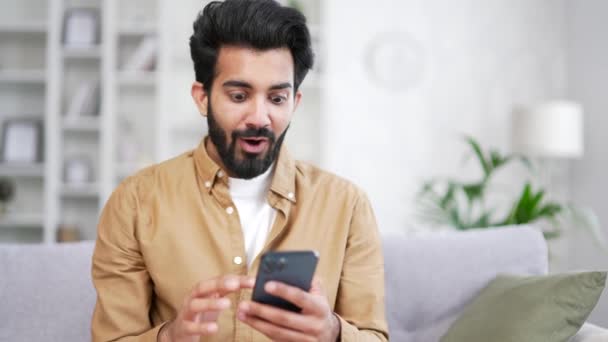 Mutlu Genç Adam Evdeki Oturma Odasındaki Kanepede Otururken Akıllı Telefondan — Stok video