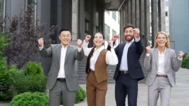 İş adamlarından oluşan mutlu ekip çalışanları başarıya sevinir. Grup çalışanı erkek ve kadın yöneticileri şehir merkezindeki bir ofis binasının yakınındaki bir caddede kameraya bakarak zaferi kutluyorlar. Dışarıda dışarıda.