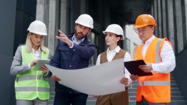 Takım tasarımcısı Yatırımcı ve inşaat mühendisi çalışanları, inşaat mühendisi inşaat mühendisi inşaat işçisi inşaat alanında mühendislik ekibi çizimlerine bakarak iletişim kuruyor.