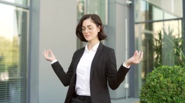 Resmi takım elbiseli genç bir iş kadını, kapalı gözlerle meditasyon yapıyor. Ofis binasının yakınındaki bir bankta oturuyor. Sakin bir dişi dinlenir ve huzuru hisseder. Kadın stres atmak için gevşer.