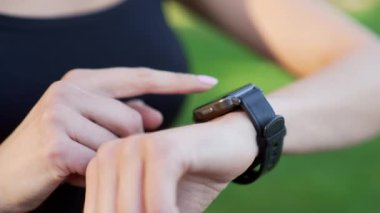 Akıllı bir saatle bir kadının elini kapat. Sporcu kadın bir fitness izleyicisi kullanıyor, dokunmatik ekranda parmağını kaydırıyor, egzersiz öncesi cihazı ayarlıyor. Formda kadın eğitim sonuçlarına bakıyor