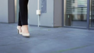Kapatın. Yüksek topuklu ayakkabılı kadın bacakları şehir caddesinde yürüyor. Siyah pantolonlu bir kadın kaldırımda yürüyor. Ayakkabılı genç iş kadınının ayakları şehre iniyor. İşe gidiyorum.