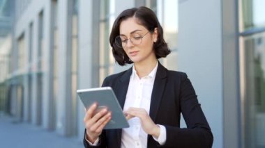 Resmi takım elbiseli genç işadamı bir ofis binasının yanında caddede dururken bir tablet kullanıyor. Kadın yönetici çevrimiçi alışveriş yapıyor, mesaj atıyor, e-postaları kontrol ediyor, sohbet ediyor veya bir kısa mesaj okuyor