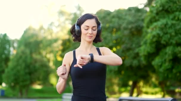 Genç Esmer Kadın Kulaklıklı Koşucu Şehir Parkında Koşuyor Akıllı Saat — Stok video
