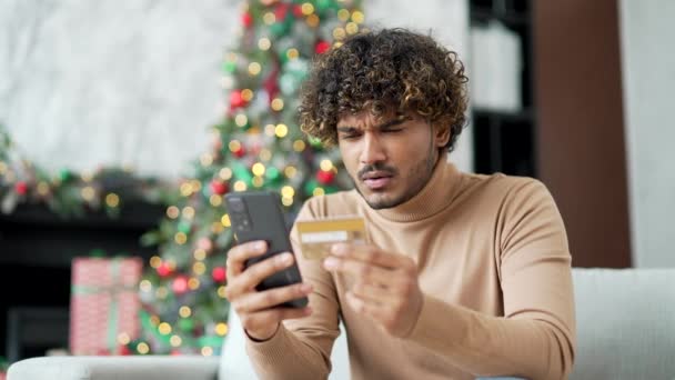 在寒假期间 沮丧的年轻人通过坐在家里的智能手机发现了信用卡号码中的欺诈行为 惊慌失措的男子看到钱是从他的账户上偷来的 — 图库视频影像