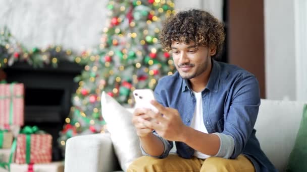 Tânăr Folosește Smartphone Timp Stă Canapea Acasă Timpul Sărbătorilor Crăciun — Videoclip de stoc