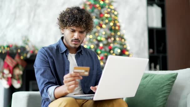 混乱した若者は 冬のクリスマス休暇中に自宅に座っているラップトップにクレジットカード番号を入力しながら詐欺を発見しました 男は彼の口座からお金が盗まれたのを見た — ストック動画