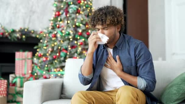 新年假期 年轻人在家里沙发上坐着咳嗽 感冒或流感的病人感觉很糟 用手帕擦鼻涕 他有高烧或支气管炎 — 图库视频影像