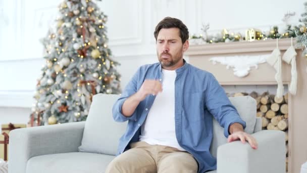 吐き気で苦しんでいる男性は 冬のクリスマスXmas休暇中に家のリビングルームでソファーに座って嘔吐したいです 不健康な男性は気分が悪く パーティーを祝った後に胃が痛みます — ストック動画