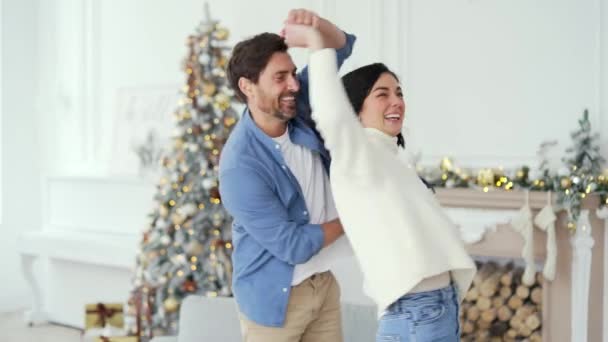 圣诞佳节期间 一对快乐的夫妇手牵着手在客厅里跳舞 玩得很开心 妻子和丈夫在跳舞 笑着打转 他们有一种节日的气氛 — 图库视频影像