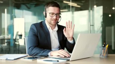Ofisteki bir iş yerinde videolu görüşme yapan kendine güvenen bir iş adamı. Girişimcinin bir iş toplantısı var. Koç çevrimiçi kurslarda, giyim kuşamında, seminerde veya konferansta uzaktan konuşuyor.