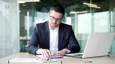 Kendine güvenen işadamı, iş yerindeki bir masada otururken belgeleri imzalıyor. Resmi takım elbiseli ciddi bir patron dosyayı tekrar okuyup sözleşmeyi imzalıyor.