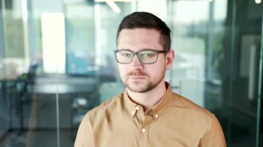 İş yerindeki iş yerinde duran gömlek ve gözlüklü ciddi başarılı iş adamının portresi. İçerideki kameraya bakarak poz veren kendine güvenen girişimci. Müdürün kafasından.